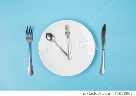 Top view white ceramic plate with knife, spoon and fork on blue background. Intermittent fasting, Ketogenic dieting, weight loss, meal plan and healthy food concept 71008002