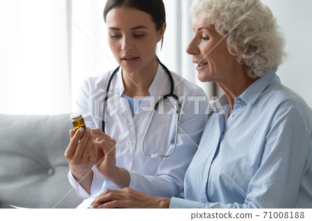 Young female doctor prescribe medicine bottle to old grandma patient Young female doctor prescribe medicine bottle to old grandma patient 71008188