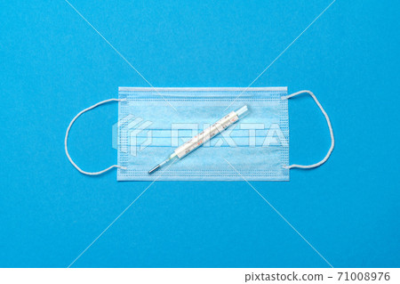 Protective medical face mask and Thermometer on a blue background - Top view with copy space Protective medical face mask and Thermometer on a blue background - Top view with copy space 71008976