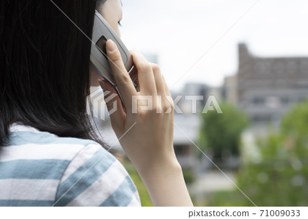 A woman calling on a feature phone outside 71009033