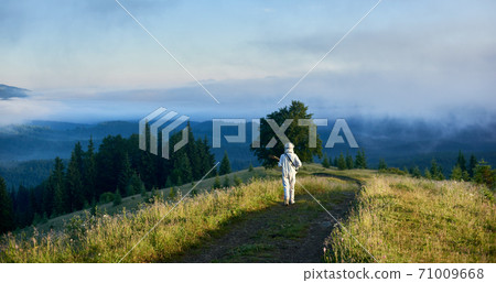 Astronaut with guitar walking down hillside path. 71009668