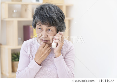 Senior woman answering a suspicious call 71011022