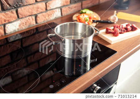 Metal pot stands on a modern induction cooker Metal pot stands on a modern induction cooker 71013214