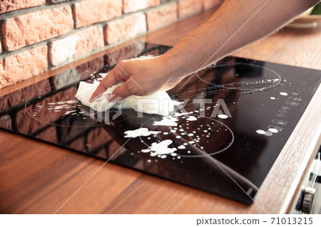 Man hand cleaning a induction cooker with some cleaning detergent Man hand cleaning a induction cooker with some cleaning detergent 71013215