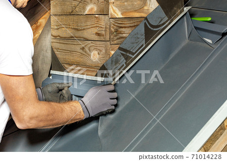 A worker is waterproofing a chimney on the roof of house. 71014228