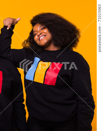 Young beautiful african american girl with an afro hairstyle. Portrait on yellow background. 71015063