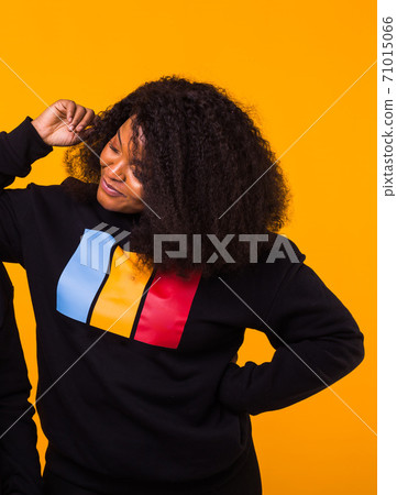 Young beautiful african american girl with an afro hairstyle. Portrait on yellow background. 71015066
