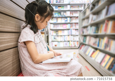 Asian cute girl 6-7 years reading a book in public library 71015738