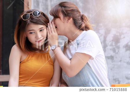 Attractive young woman whispered something to her friend.  71015888