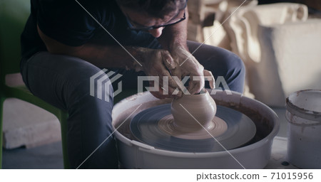 Crop ceramist creating pot from wet clay Crop ceramist creating pot from wet clay 71015956