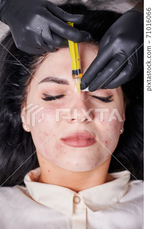 Female doctor making injection in nose of young woman 71016066