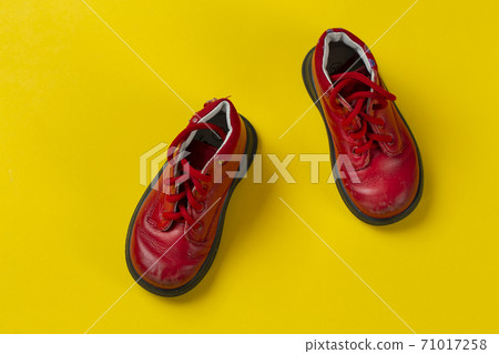Children's leather shoes in red on a yellow background. Care for health. 71017258
