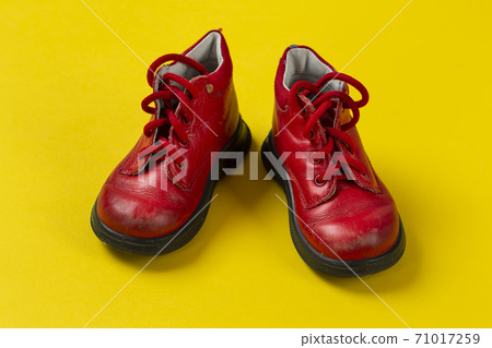 Children's leather shoes in red on a yellow background. Care for health. 71017259
