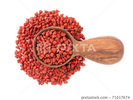 Annatto seeds in wooden spoon, isolated on white background. Achiote seeds, bixa orellana. Natural dye for cooking and food. Top view. 71017674