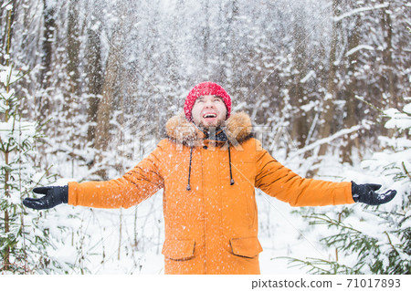 Young man throwing snow in winter forest. Guy having fun outdoors. Winter activities. Young man throwing snow in winter forest. Guy having fun outdoors. Winter activities. 71017893