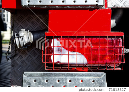 Rear brake light in the protective metal grill of a fire truck, close up. 71018827
