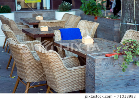 wooden tables and wicker chairs fenced with large flowerpots with flowers, nobody. wooden tables and wicker chairs fenced with large flowerpots with flowers, nobody. 71018988
