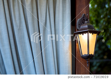 forged iron lantern, sconce outdoor lighting close-up against curtain. forged iron lantern, sconce outdoor lighting close-up against curtain. 71019019