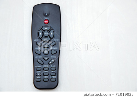 The remote control of the projector lies on a wooden table top view, close-up of the device with copy space for text. 71019023