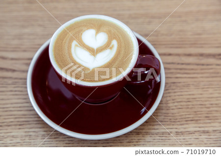 brown cup on a saucer with coffee cocktail and milk froth on a wooden table. brown cup on a saucer with coffee cocktail and milk froth on a wooden table. 71019710