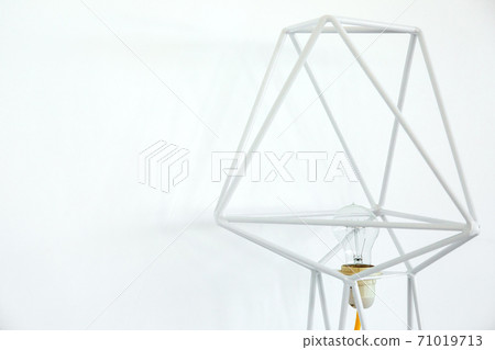 frame chandelier from white metal rods with a light bulb against a white wall with copy space. frame chandelier from white metal rods with a light bulb against a white wall with copy space. 71019713