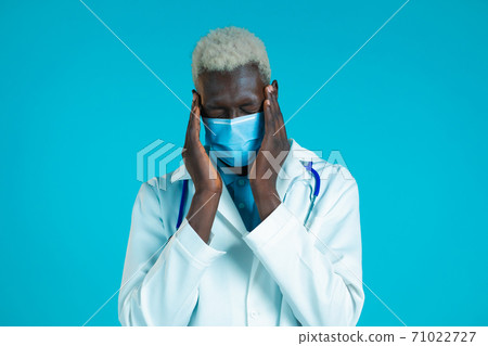 Young african doctor man in professional medical white coat having headache, studio portrait. Guy Young african doctor man in professional medical white coat having headache, studio portrait. Guy 71022727
