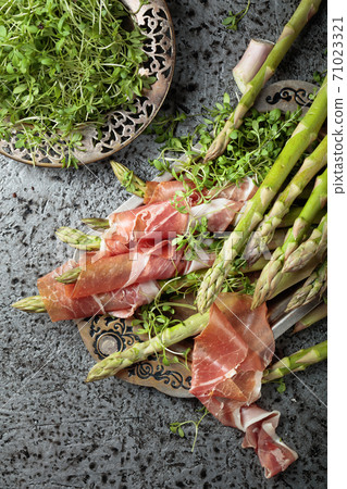 Asparagus wrapped in prosciutto with cress salad . Asparagus wrapped in prosciutto with cress salad . 71023321