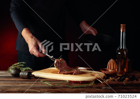 Chef prepare steak. Uncooked steak in sauce with spices an rosemary. 71023524