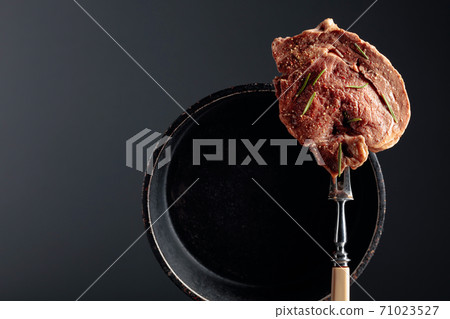 Uncooked steak in sauce with spices an rosemary. Uncooked steak in sauce with spices an rosemary. 71023527
