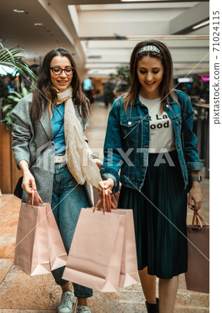 Trade, buyers. Two beautiful girls make purchases in a shopping center, go shopping. The joy of consumption. Trade, buyers. Two beautiful girls make purchases in a shopping center, go shopping. The joy of consumption. 71024115