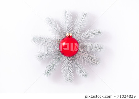 Conceptual photo. White hand painted spruce branches frame a beautiful glossy red Christmas ball with space for inscription. 71024829