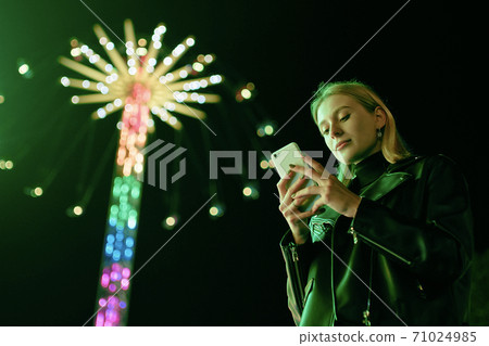 Blond Woman Surf Internet On Smartphone in Amusement Park Blond Woman Surf Internet On Smartphone in Amusement Park 71024985