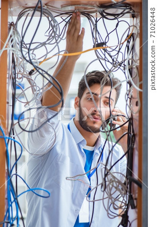 Electrician trying to untangle wires in repair concept Electrician trying to untangle wires in repair concept 71026448