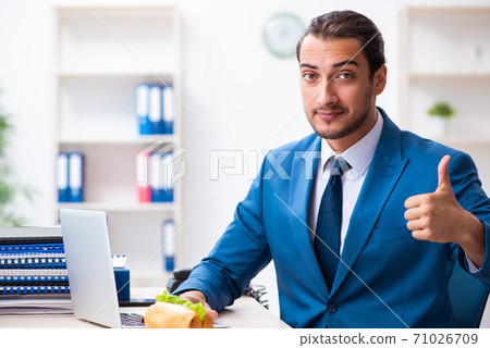 Young male employee having breakfast at workplace 71026709