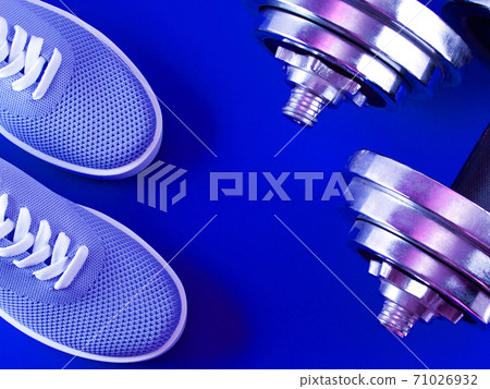 Blue sneakers on ultramarine color background with dumbbells. Blue sneakers on ultramarine color background with dumbbells. 71026932