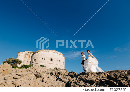 bride and groom are standing together and holding hands near the Arza fortress on the Mamula island bride and groom are standing together and holding hands near the Arza fortress on the Mamula island 71027861