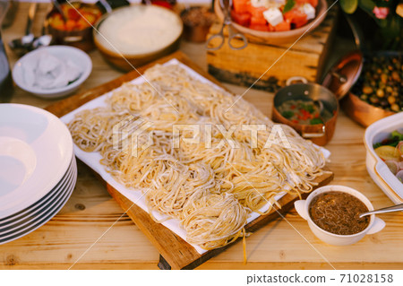 Spaghetti on a wooden plank for cutting with cooked meals and clean plates. Spaghetti on a wooden plank for cutting with cooked meals and clean plates. 71028158