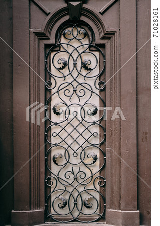 A window with a metal grille with patterns with a lilac sheen. A window with a metal grille with patterns with a lilac sheen. 71028161