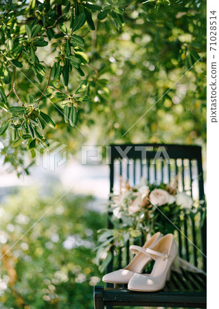 A chair with shoes and a bridal bouquet under the resin seed tree with fruits on the tree. 71028514
