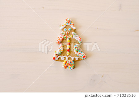 Gingerbread cookies in the shape of a Christmas tree, decorated with glaze and colored sprinkles, on a white painted wood texture. Gingerbread cookies in the shape of a Christmas tree, decorated with glaze and colored sprinkles, on a white painted wood texture. 71028516