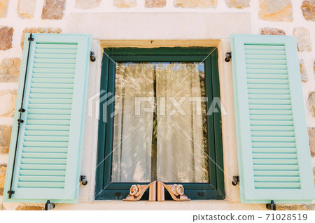 Women's clogs with a large buckle on the side on the window with open shutters on the outside. Women's clogs with a large buckle on the side on the window with open shutters on the outside. 71028519