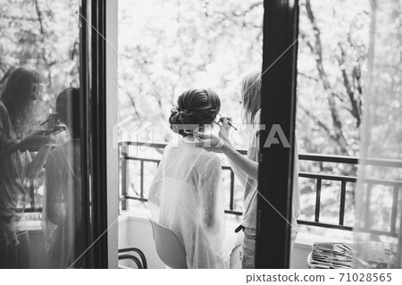 makeup artist does makeup to the bride during the preparation for the ceremony 71028565