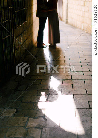 A loving couple in an alley between houses on paving slabs. A loving couple in an alley between houses on paving slabs. 71028620