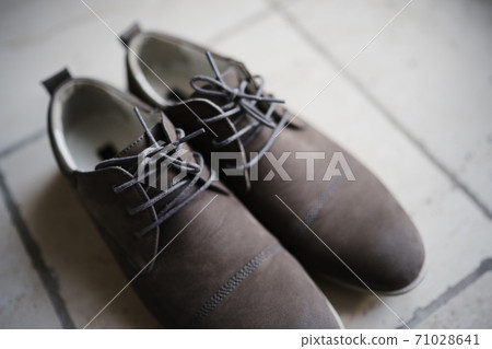Men's gray suede shoes with laces on the floor with shallow depth of field. Men's gray suede shoes with laces on the floor with shallow depth of field. 71028641