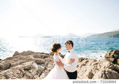 bride and groom are hugging on the rocky beach of the Mamula island near Arza fortress bride and groom are hugging on the rocky beach of the Mamula island near Arza fortress 71028664