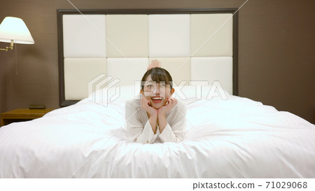Woman frolicking on the hotel bed 71029068