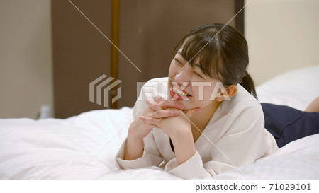 Woman frolicking on the hotel bed 71029101