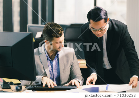 Two business man talking with partner mix race Asian and Caucasian male, Boss executive working help care with employee in office. 71030258