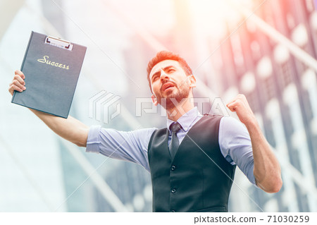 Successful latin businessman glad expression hand rising outdoors at business office outdoors. Successful latin businessman glad expression hand rising outdoors at business office outdoors. 71030259