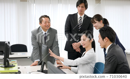 A businessman who looks at a computer and discusses 71030640